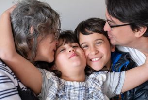 A joyful family of four sharing a warm embrace, highlighting love and togetherness indoors.